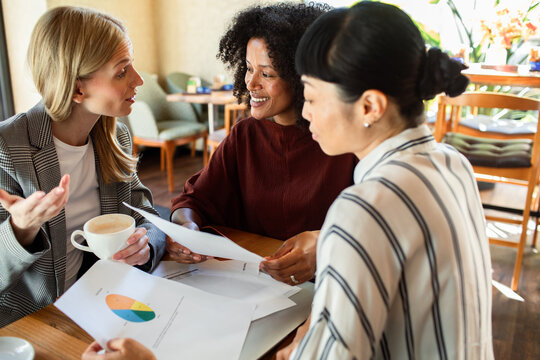 Three businesswomen discussing charts at a cafe
