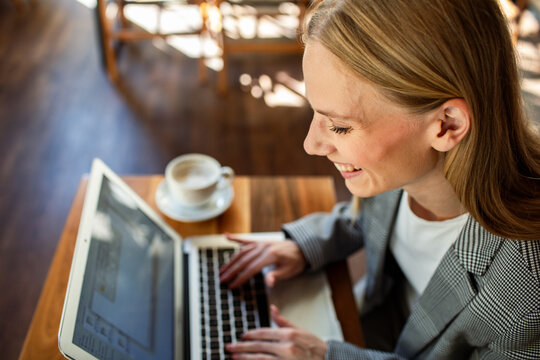 Smiling businesswoman typing on laptop in coffee shop