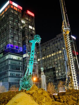 Construction of the Piața Presei Libere metro station in Bucharest includes tunnel drilling at night with large machinery operating in an urban setting surrounded by modern skyscrapers