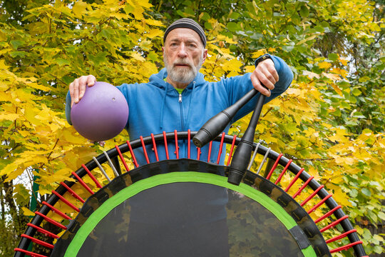 senior man with a medicine ball, In dian clubs and a mini trampoline for fitness exercising and rebounding, fall backyard  scenery