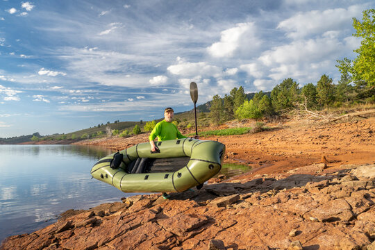 senior male paddler is launching an inflatable packraft on a shore of Horsetooth Reservoir in Colorado