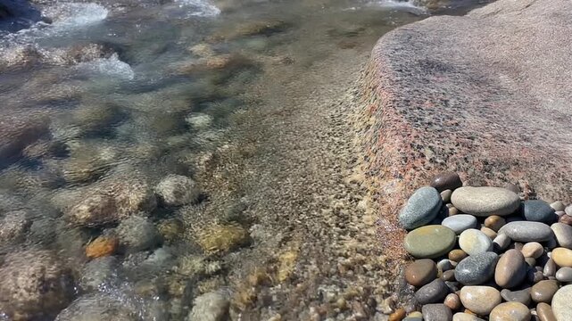礫岩の丸石が並ぶ岩肌を流れる水 シームレスループ動画背景 16:9 4K