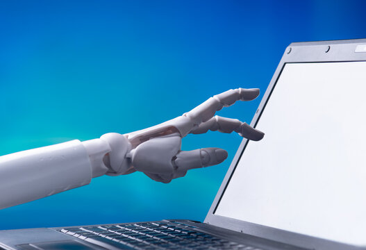 Robotic hand pointing at laptop blank screen with blue background for AI technology