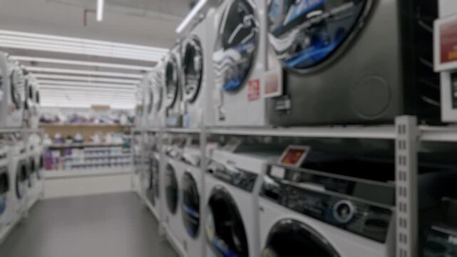 Defocused view inside a large electronics store showing rows of modern washing machines and irons on display, creating an abstract background for retail and consumerism concepts