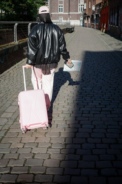 Traveller with luggage on cobblestone lane