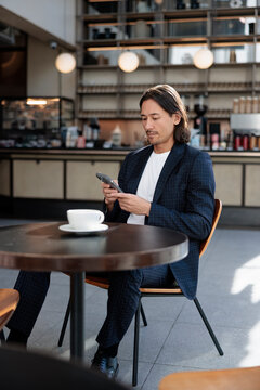 Man in suit uses phone at cafe table