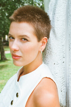 Young Woman With Short Hair Stands Outdoors by a Tree