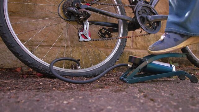Cyclist pumping flat tyre on bicycle