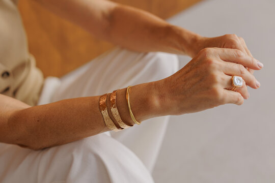 Woman wearing elegant gold bracelets and pearl ring
