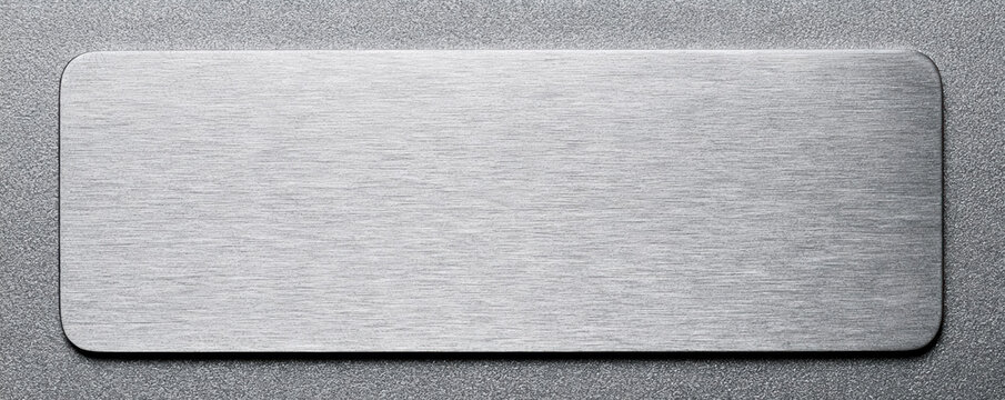 Brushed metal plate on textured surface with rounded corners and smooth finish, ideal for industrial or design use