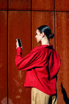 Woman checking smartphone beside paneled wall in film photo