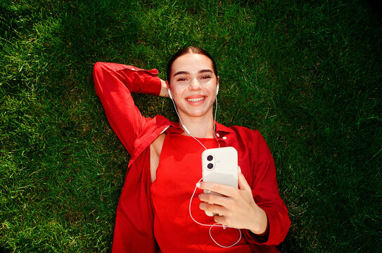 Woman listening to music while lying on grass in film photo