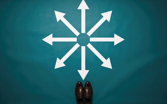 Top-down view of brown leather shoes standing before a white eight-pointed arrow star on a teal background