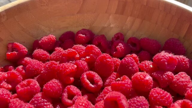  Fresh ripe red raspberries in a wooden bowl on a wooden table