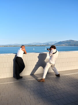 Photographer shooting model outdoors by ocean water