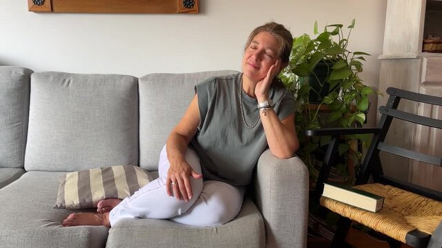 Mature woman relaxing at home on the sofa enjoying a peaceful moment of serenity and well being