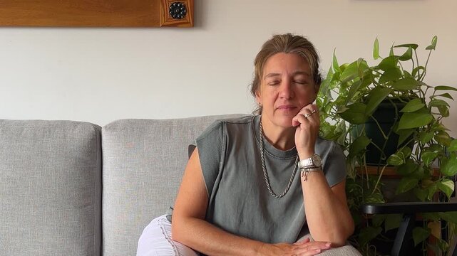 Serene mid adult woman relaxing on the couch in her living room.