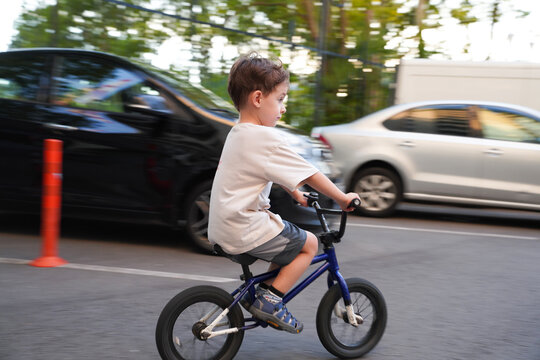 Boy Riding a Bike Next to Moving Cars