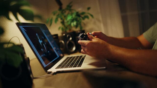 Creative photographer holding a retro film camera while post-processing black and white images on a laptop computer, working late at night in a dimly lit home studio workspace