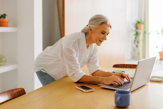 Mature woman working remotely using laptop at home