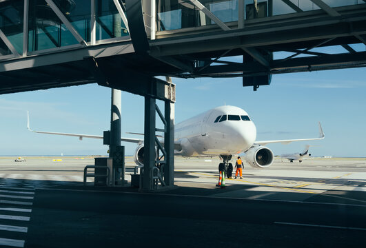 Passenger airplane at airport gate beneath boarding bridge