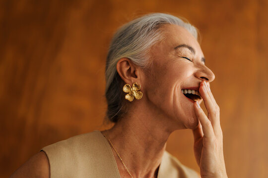 Senior woman laughing covering mouth with hand