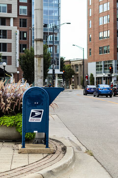 Champaign, Illinois - August 29, 2026: A blue United States Postal Service (USPS) collection box on a city sidewalk next to a street.