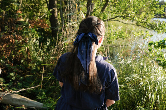 Person Standing Near Water Surrounded by Trees and Plants