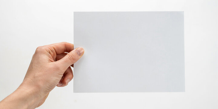 A hand holding a blank white rectangular card against a plain white background, for copy space area