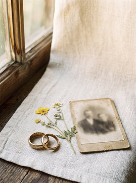 Two aged gold rings and pressed flower on linen with nostalgic warm sentimental mood generative AI