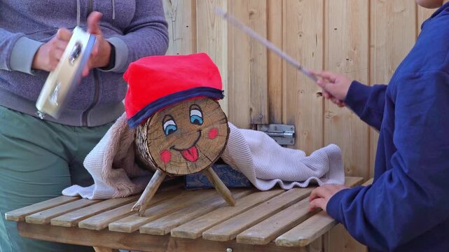 A mother and son hitting Christmas log while singing the traditional song Caga Tio
