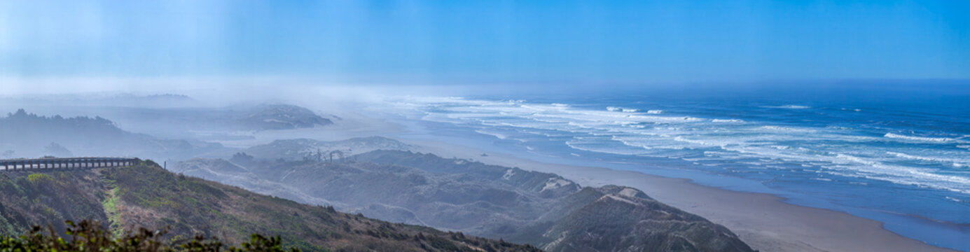 Beautiful wide panoramic view of a scenic ocean coast viewpoint next to a highway in morning fog