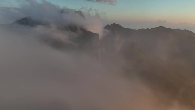 Aerial view of Foce del Pallone surrounded by clouds and mountain peaks at sunset in Stazzema, Toscana, Italy.