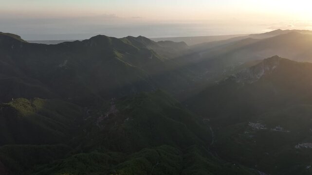 Aerial view of the rugged mountain landscape of Foce del Pallone at sunset with golden light casting long shadows over the green slopes in Stazzema, Toscana, Italy.