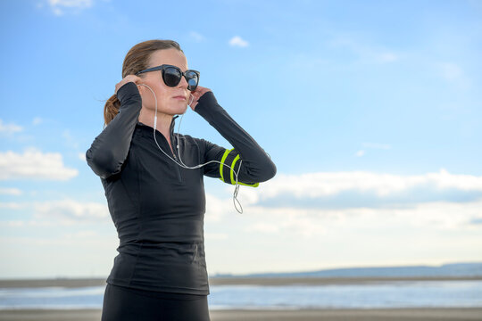 Woman Jogging on Beach with Headphones at the Coast
