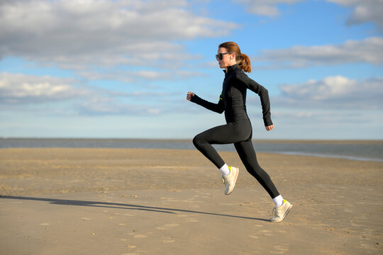 Woman Running on Beach During Autumn Evening