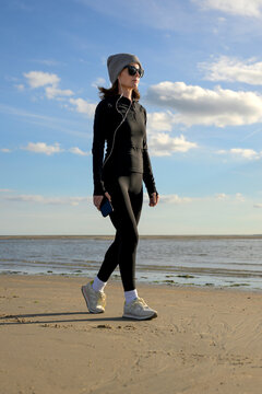 Woman in Sportswear Walking on Beach at Sunset