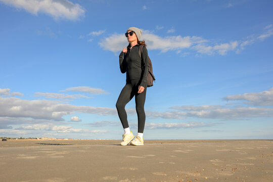 Woman in Winter Fitness Gear Walking on Beach