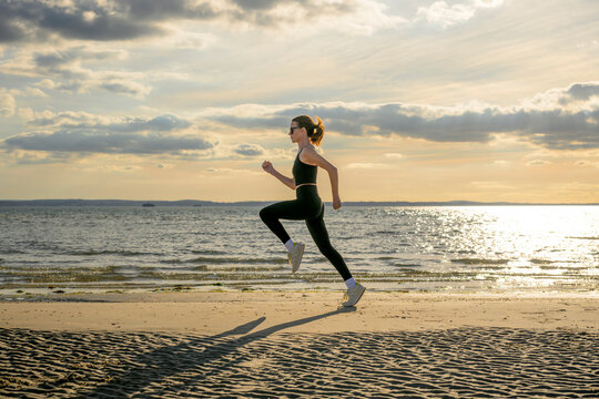 Woman Jogging on Sandy Beach at Sunset