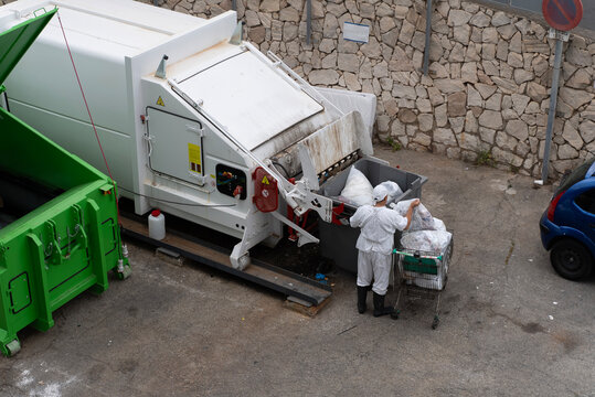 Waste Collection Worker Loading Garbage Into Compactor Truck