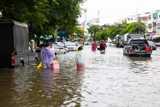 Asian boy wearing Raincoat and mother waded through floodwaters to go buy food, lifestyle of Thai people in massive flooding, Severe weather