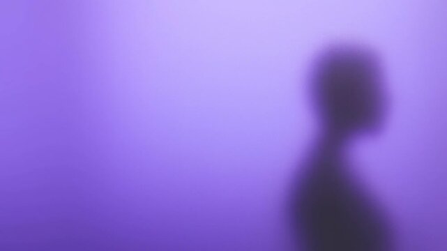 Blurred silhouette shifts behind a translucent purple surface in an abstract illuminated setting
