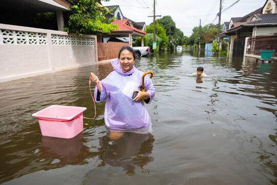 obese woman wearing Raincoat and walking through flood waters to go buy food, lifestyle of Thai people in massive flooding, Severe weather