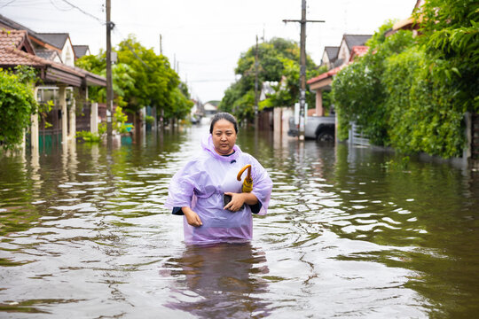 obese woman wearing Raincoat and walking through flood waters to go buy food, lifestyle of Thai people in massive flooding, Severe weather