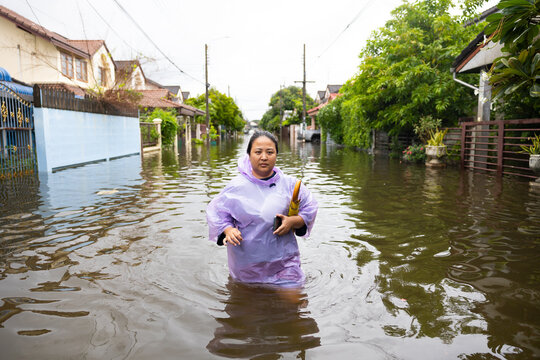 obese woman wearing Raincoat and walking through flood waters to go buy food, lifestyle of Thai people in massive flooding, Severe weather