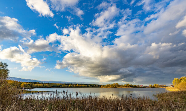 Golden reeds frame a calm lake under a vast sky