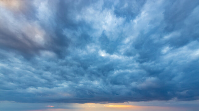 Dramatic clouds swirl in deep blue and gray hues