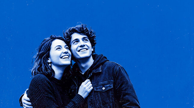 Happy young couple embracing and looking up on vibrant blue halftone background