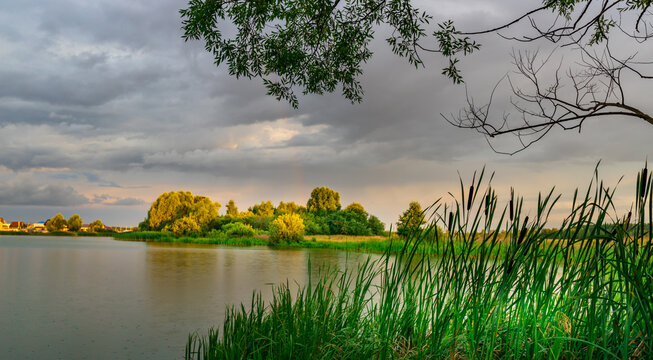 Serene lake reflects golden light under stormy sky