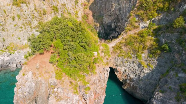 San Nicola Arcella Calabria Italy 4k drone view of Arcomagno hidden beach path. Vertical rocky passage and staircase between cliffs to secret sea cove on Tyrrhenian coast b-roll establishing video